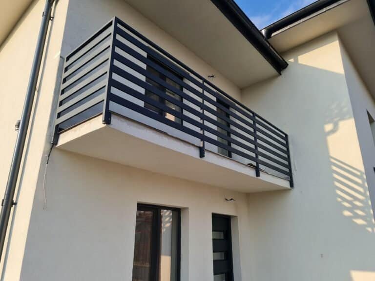 Balcon cu balustradă din metal negru, montat pe fațada unei case moderne.