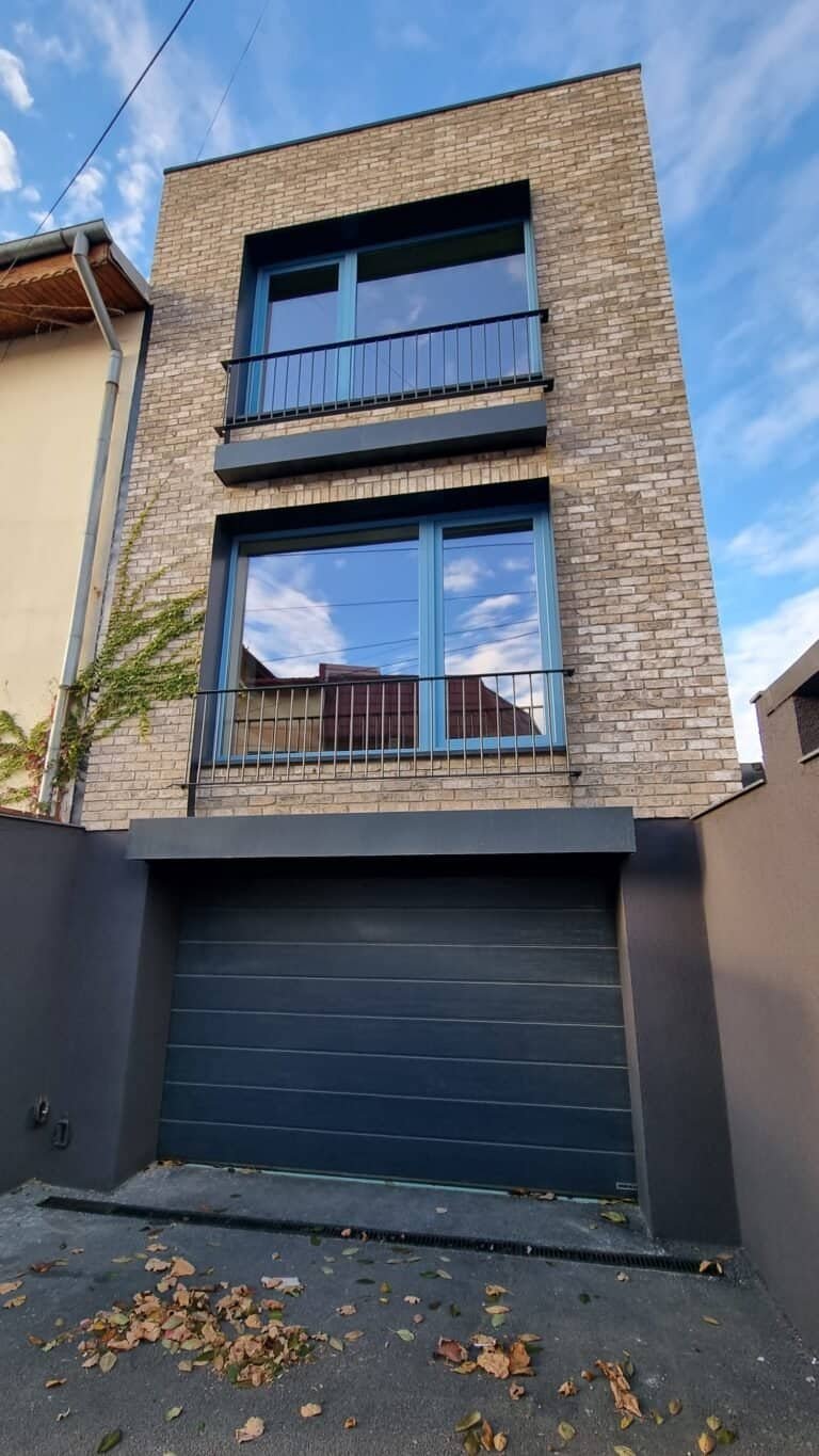 Casă modernă cu fațadă din cărămidă și ferestre mari, ideală pentru design urban contemporan.