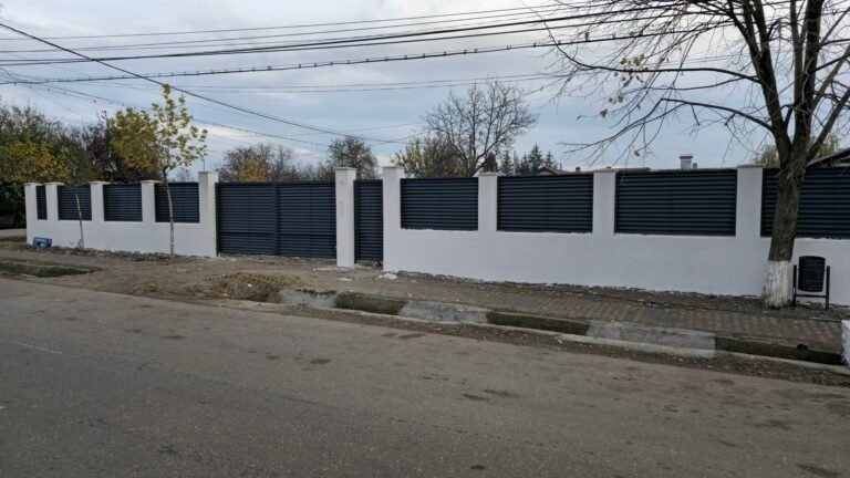 Gard modern cu stâlpi și panouri din lemn și metal, pe stradă.
