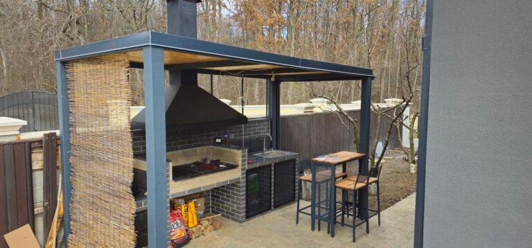 Grătar exterior cu acoperiș și zonă de luat masa în grădină.