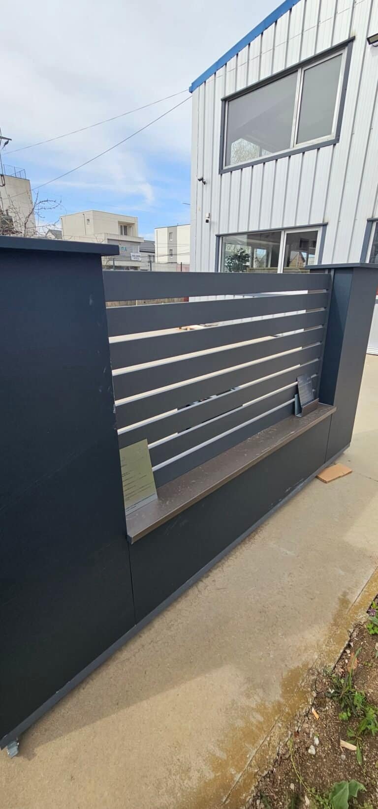 Foaie de gard din metal modernă cu dungi orizontale, instalată în mediul urban.