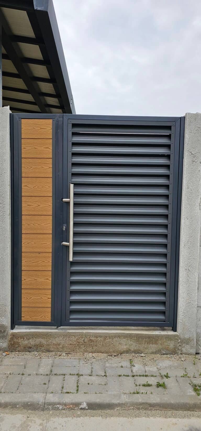 Ușă metalică cu obloane și decor din lemn pentru exterior.