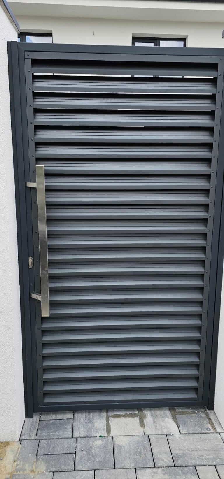 Ușă metalică gri cu grilaj pentru securitate și design modern.