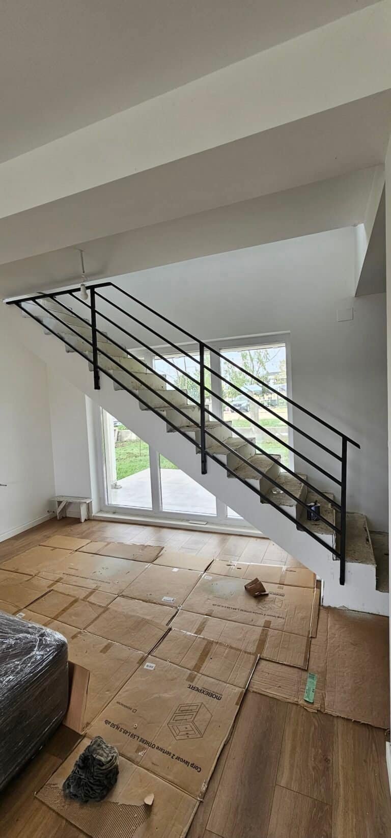 Scară interioară modernă cu balustradă neagră și trepte din lemn.