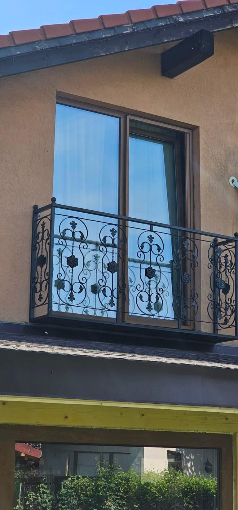 Balcon cu balustradă ornamentală din metal negru, montat pe fațada unei case moderne.