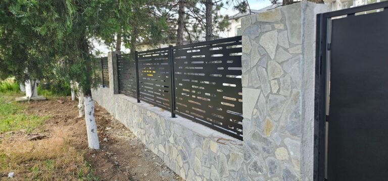 Punte de gard modernă cu panouri metalice negre și zid de piatră pentru securitate și estetică.