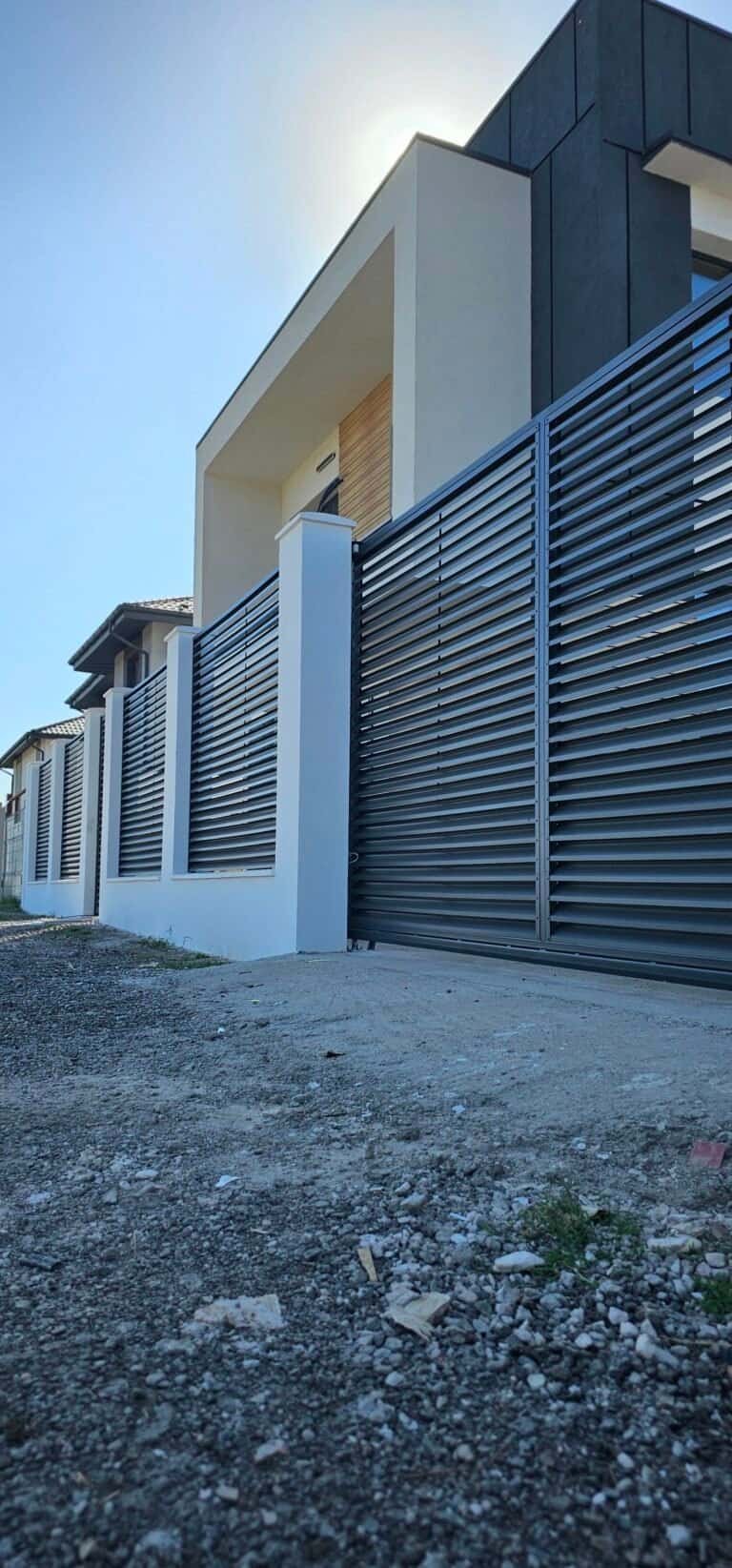 Casă modernă cu gard metalic și fațadă minimalistă, design contemporan.