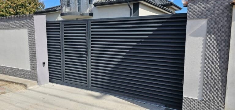 Poartă de garaj metalică neagră cu design vertical și sistem automatizat.