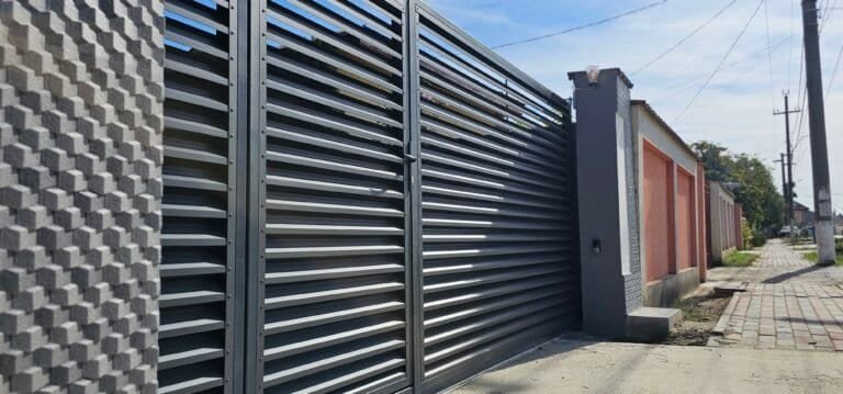 Poze cu gard din oțel negru, modern și durabil, instalat pe o stradă urbană.