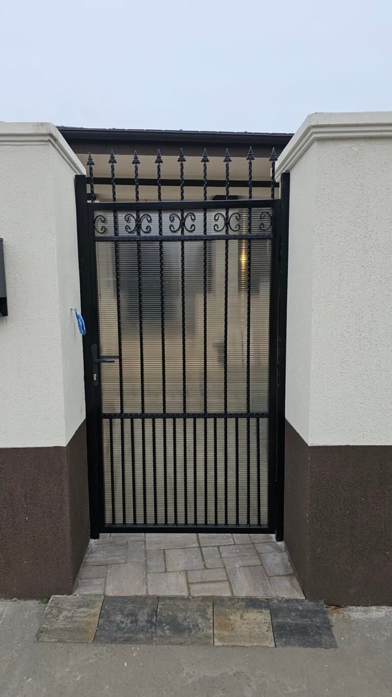Poartă metalică neagră cu design ornamental pentru intrare în curte.
