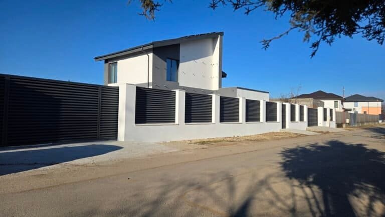 Casa modernă cu gard în stil minimalist, pe o stradă liniștită din România.