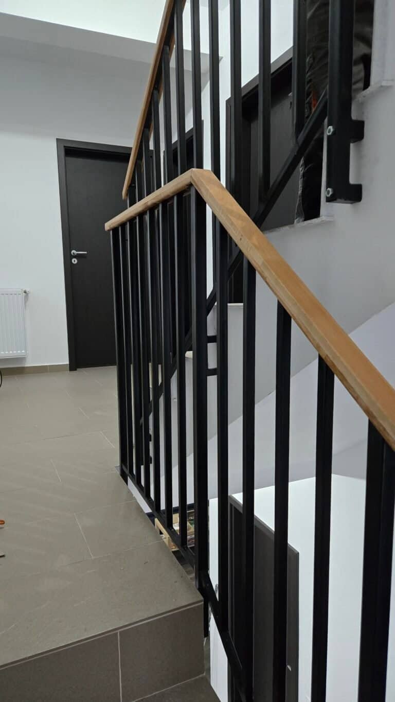 Parapet de scară din metal negru și balustradă din lemn natural.