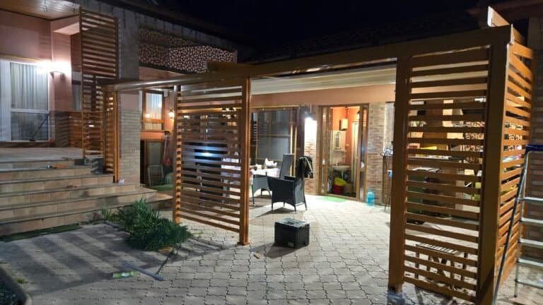 Tendință modernă în design exterior cu pergolă din lemn și iluminat ambiental.