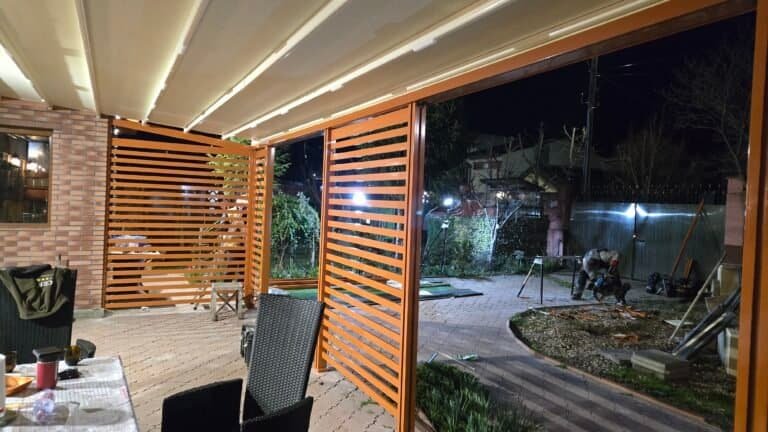 Imaginea prezintă o terasă modernă cu panouri din lemn și iluminat ambiental, ideală pentru relaxare.