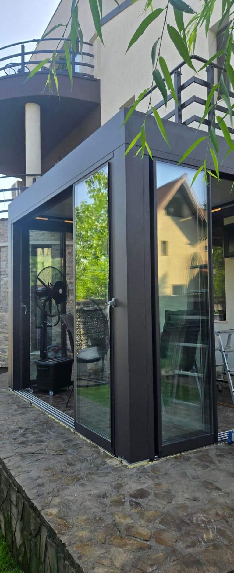 Terasă modernă cu pereți de sticlă și elemente metalice.