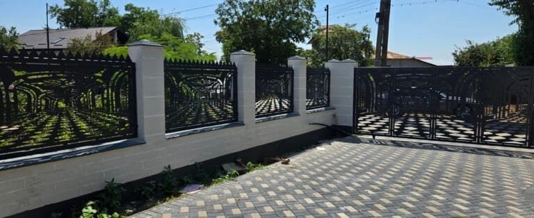 Poartă și gard din fier forjat negru cu zidărie albă, ideal pentru securitate și estetică.