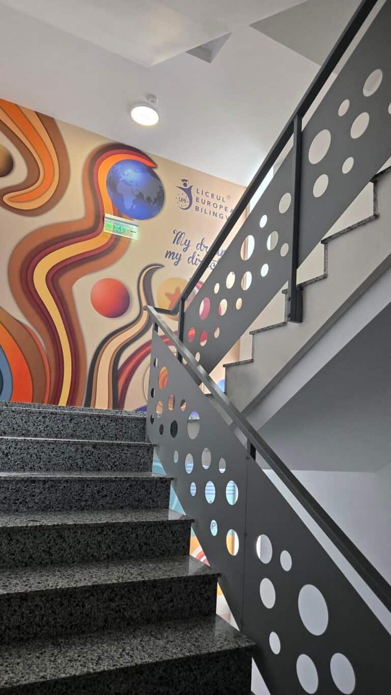 Scară modernă cu balustradă decorativă și mural vibrant pe perete.