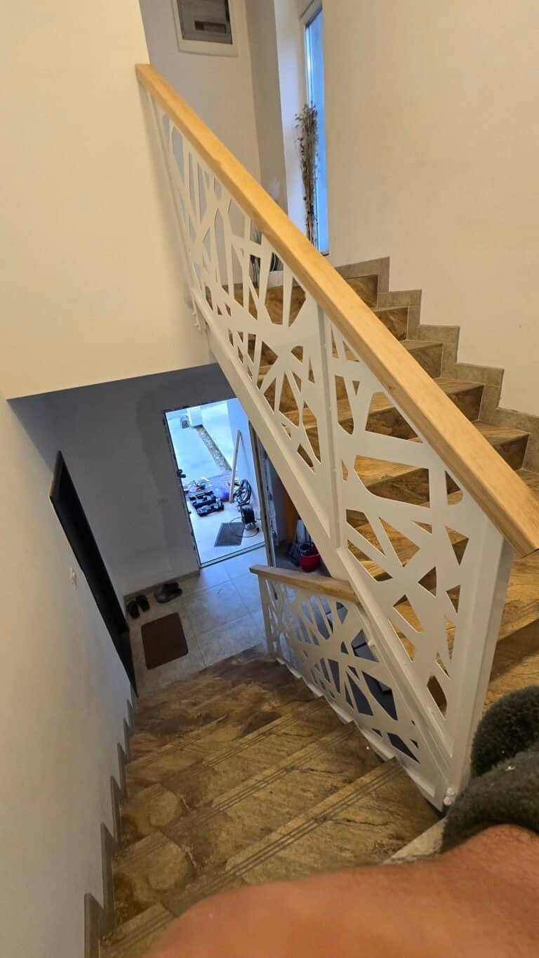 Scară interioară modernă cu balustradă decorativă din lemn și metal.