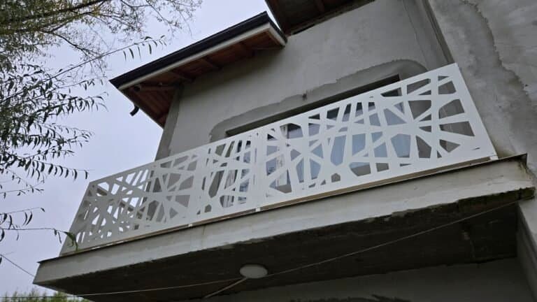 Balcon decorativ din metal alb, cu design geometric, pentru fațada casei.