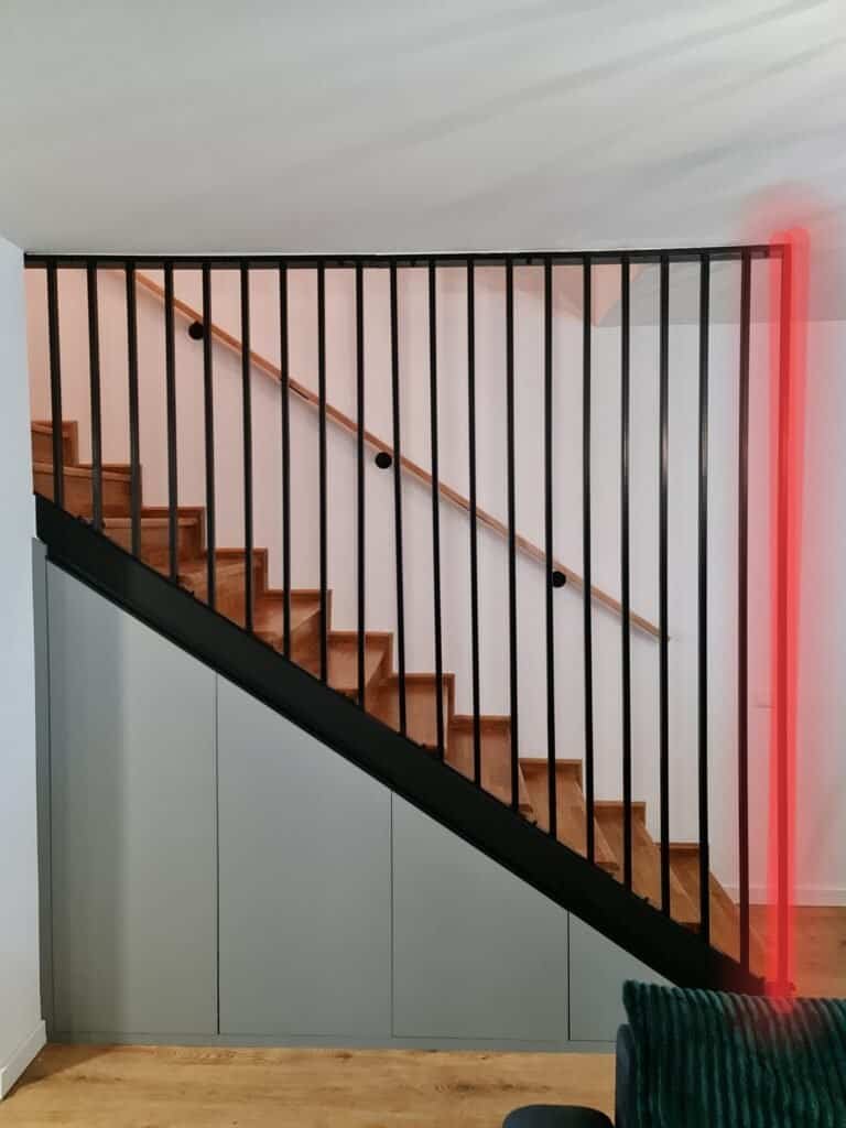 Scară interioară cu balustradă din metal negru și trepte din lemn, într-un spațiu modern și luminos.