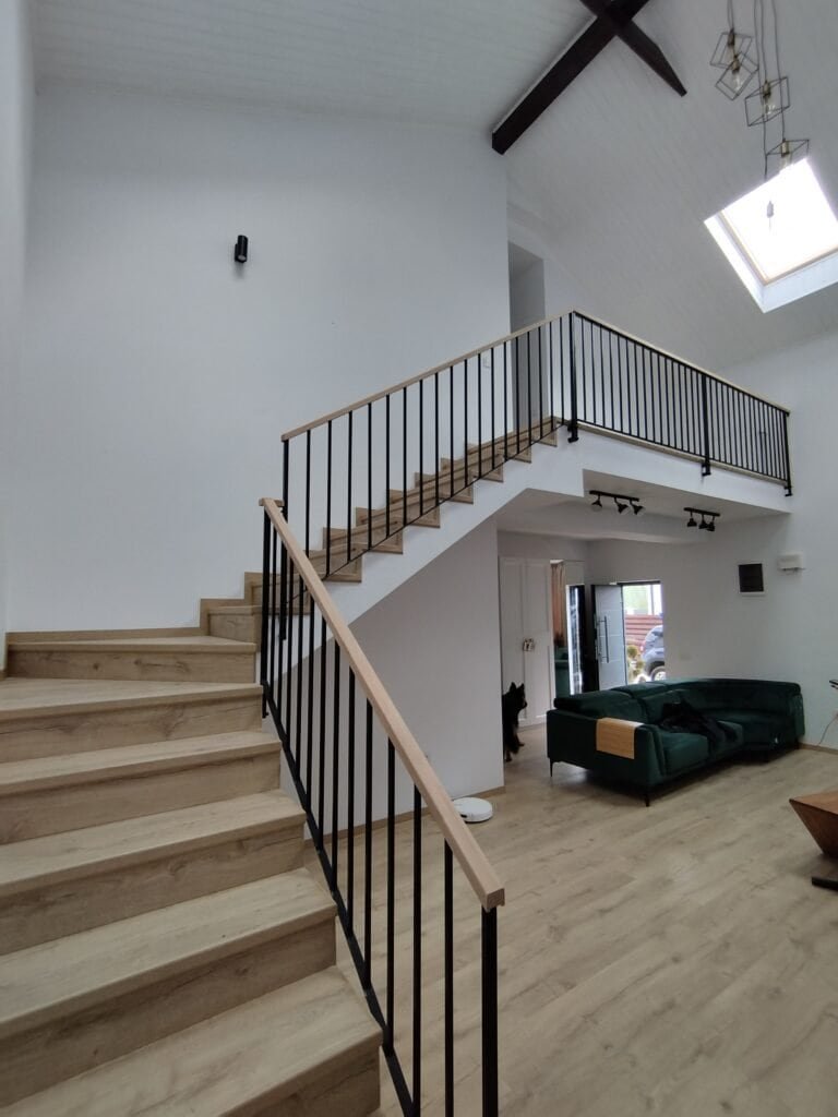 Scară interioară modernă cu balustradă din metal și lemn, în living luminos și spațios, cu ferestre.
